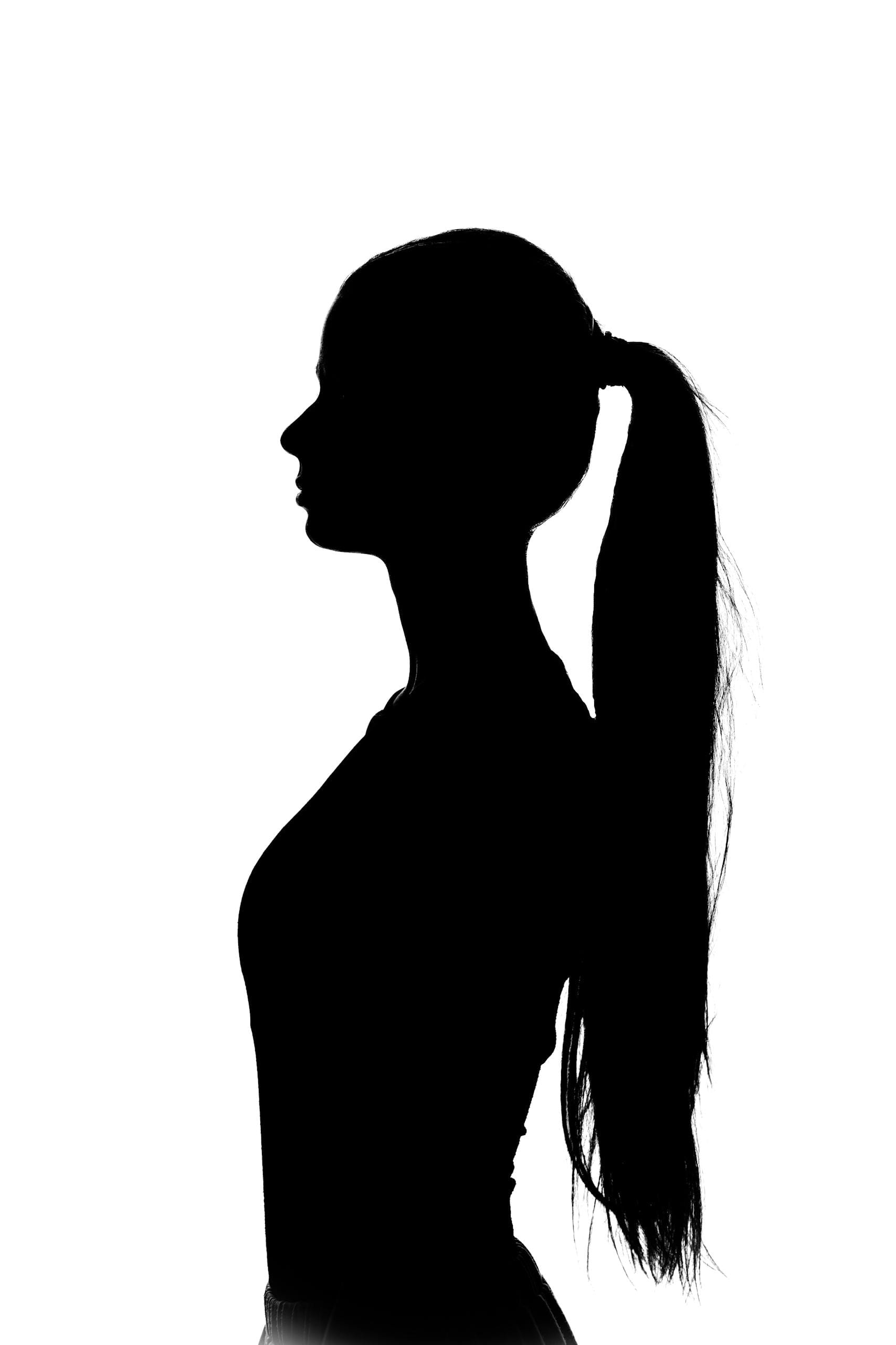 Artistic silhouette of a woman with long ponytail against white background.