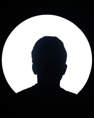 Artistic silhouette of an unknown person against a bright circular light background.